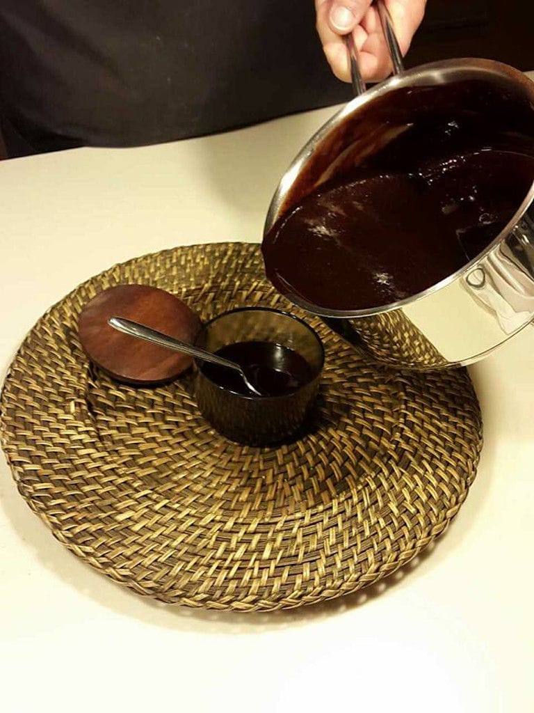 woman pouring chocolate liquid from the saucepan in a small bowl at 'The Trinity Farm'